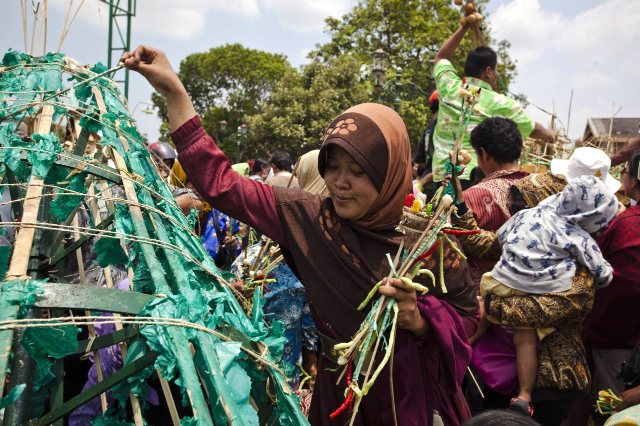  A Javanese woman picks vegetables from the Gunungan, a structure in the shape of a mountain, during the Grebeg ritual as part of celebrations for Eid al-Adha on Friday in Yogyakarta, Indonesia. People offer vegetables, peppers, eggs, and other items at the Grand Mosque and receive part of the Gunungan to be blessed in the year ahead. 