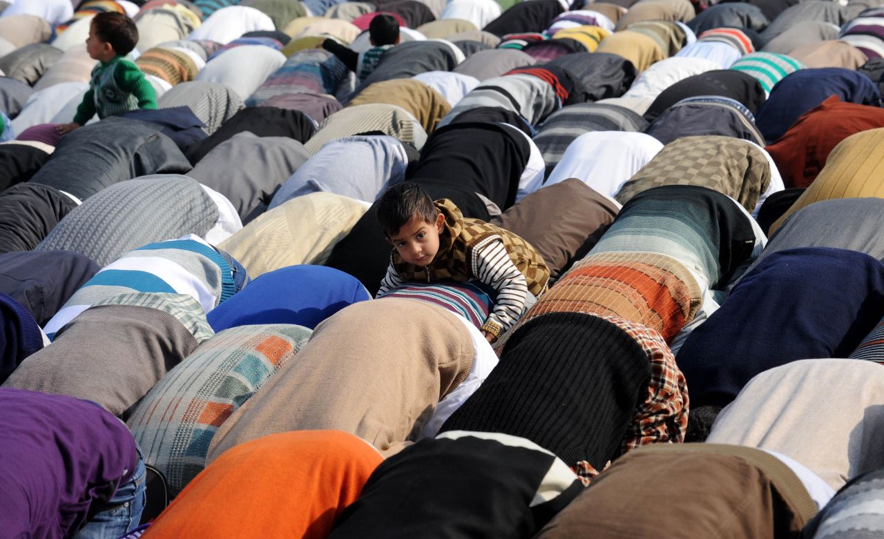 An boy climbs on the back of a praying adult in Srinagar, India, on Saturday.
