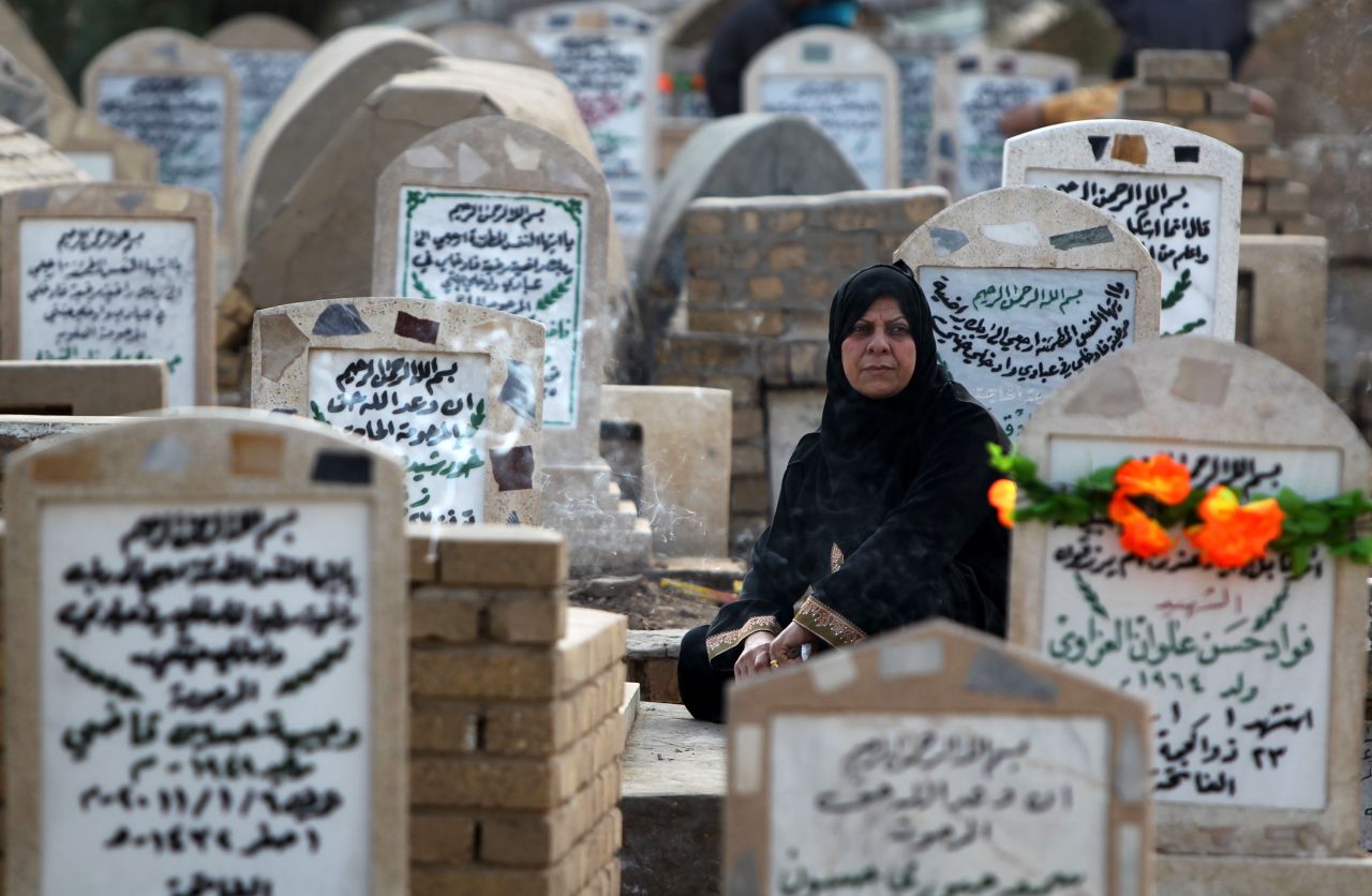 An Iraqi woman sits next to the grave of a relative on Friday at the al-Ghazali cemetery in Baghdad.
