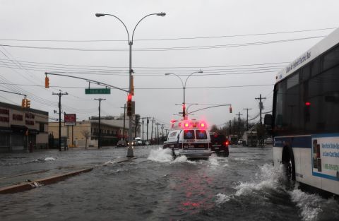 An ambulance maneuvers through water on Rockaway Beach Boulevard in Queens as the weather sours Monday in New York City.