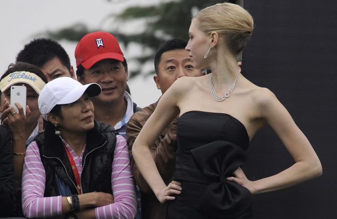 Local golf fans talk with one of the models who inhabited the greens in their evening wear in scenes seldom seen on any golf course. 