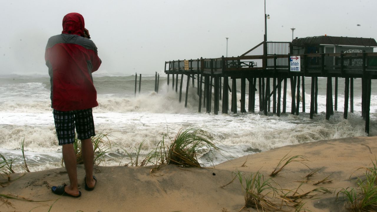 A man watches as the tidal surge pounds a pier in Ocean City, Maryland, on Monday.