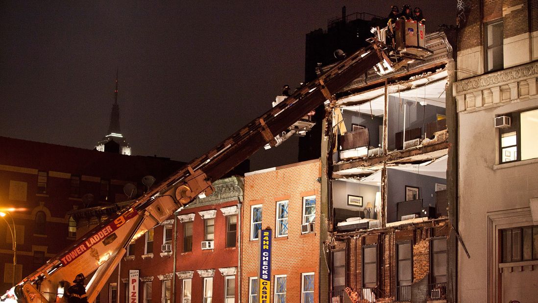 Firefighters evaluate an apartment building in New York that had the front wall collapse during the storm on Monday.