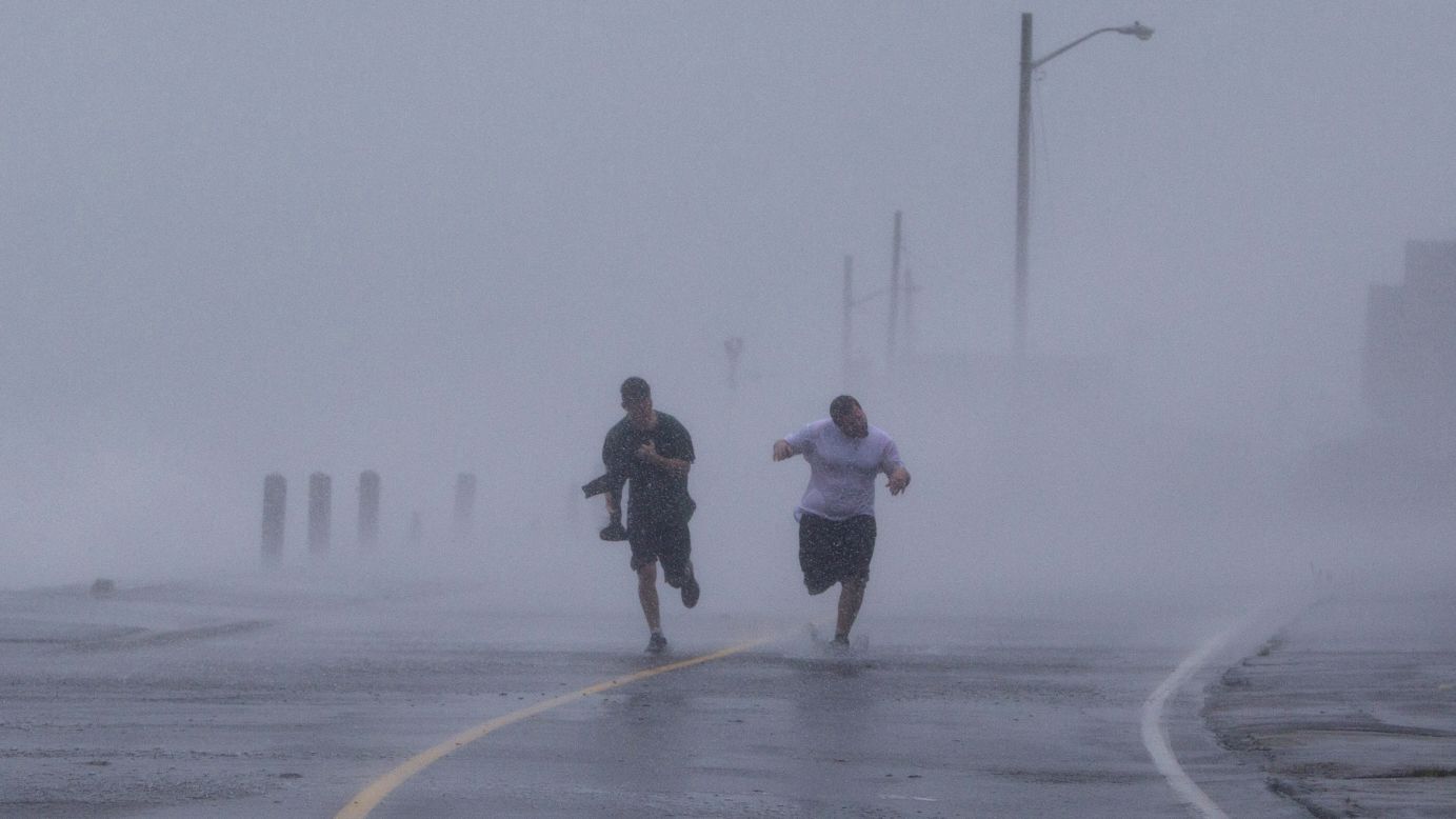 Two men run down Foster Avenue while dodging high winds and waves from the storm on Monday in Marshfield, Massachusetts.