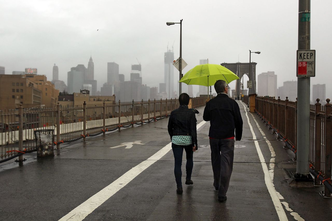 People take a Tuesday morning walk on the Brooklyn Bridge, which remains closed to traffic after the city awakened to the storm damage.