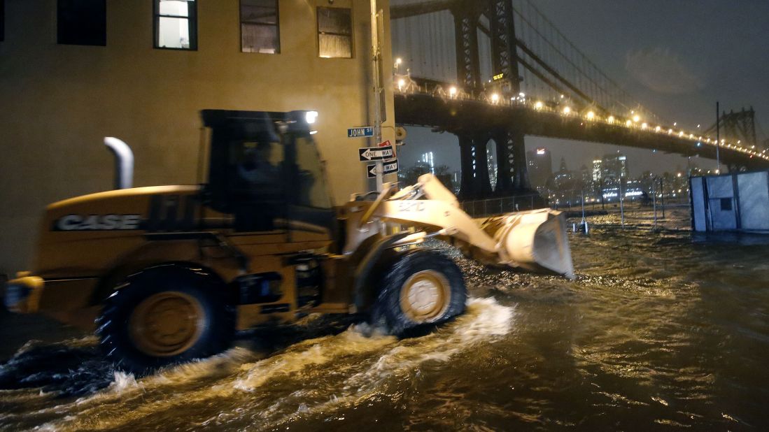 A construction vehicle drives through flooded streets in Brooklyn on Monday as Sandy makes its way north.