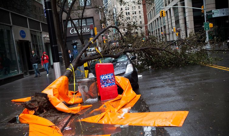 A car sits crushed by a tree in the Financial District on Tuesday. <a href="index.php?page=&url=http%3A%2F%2Fwww.cnn.com%2F2012%2F10%2F29%2Fus%2Fgallery%2Fny-braces-sandy%2Findex.html"><strong>Photos: New York braces for Sandy</strong></a><strong>.</strong>