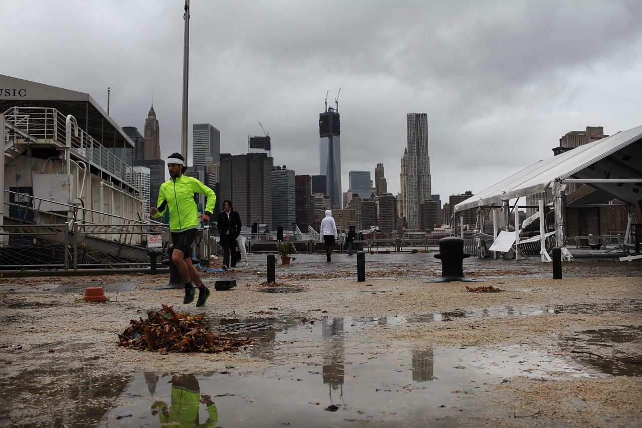 A man jogs near a darkened Manhattan skyline on Tuesday after much of New York City lost electricity.