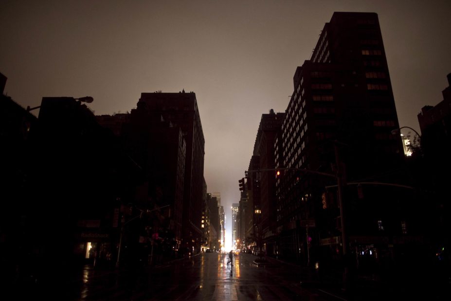 A pedestrian walks across a New York street where the power was out late Monday. The storm surge set records in Lower Manhattan, where flooded substations caused a widespread power outage.