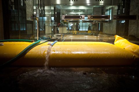 Floodwater is pumped out of a building in the financial district of New York on Monday evening.
