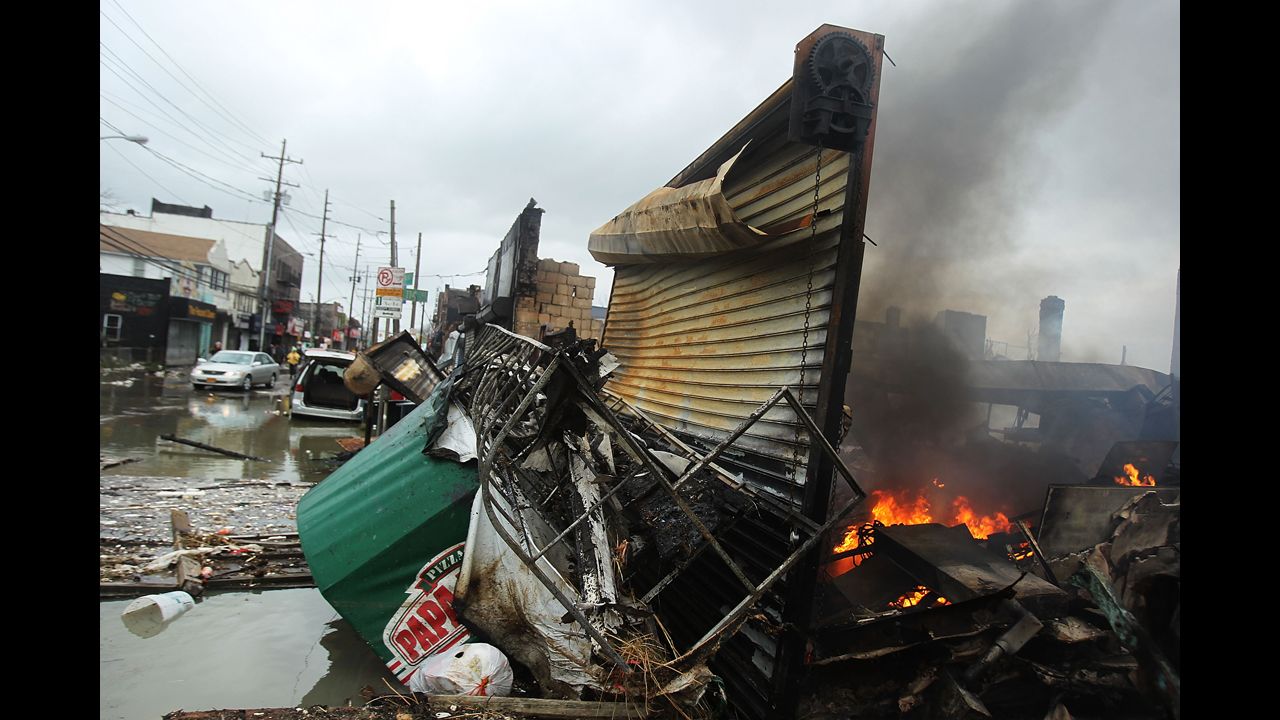 A fire continues to burn Tuesday in the remains of a structure that was destroyed by the Breezy Point blaze.