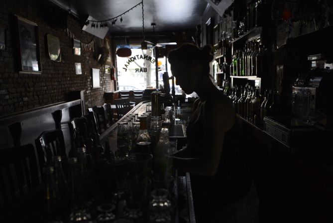 A bartender at the International Bar in the East Village neighborhood of New York City makes drinks in the dark on Tuesday as electricity remains out for many in the city.