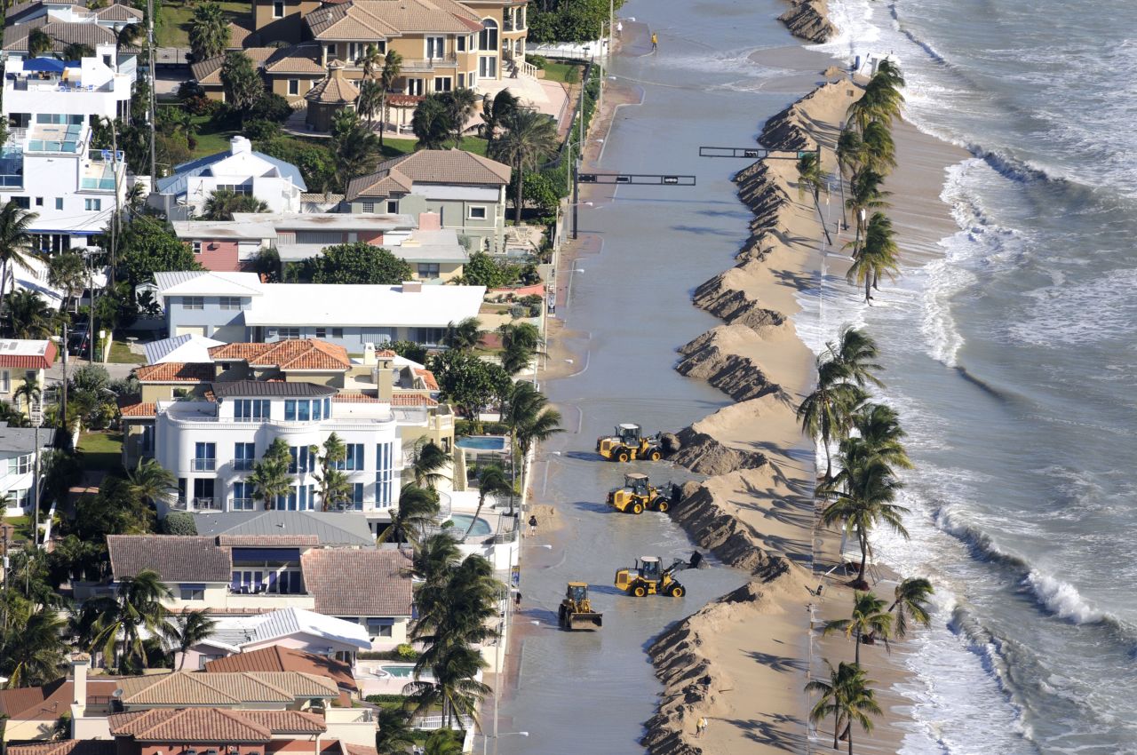 Work crews push sand from a roadway in Fort Lauderdale, Florida, due to storm surge related to flooding on Monday.
