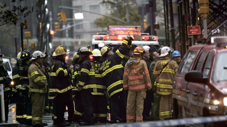 New York City firefighters and emergency workers view a collapsing crane hanging from a 90-story residential building in New York on Monday.