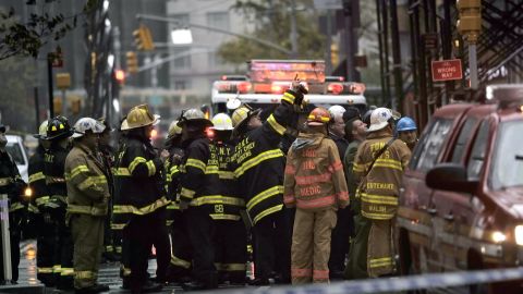 New York City firefighters and emergency workers view a collapsing crane hanging from a 90-story residential building in New York on Monday.