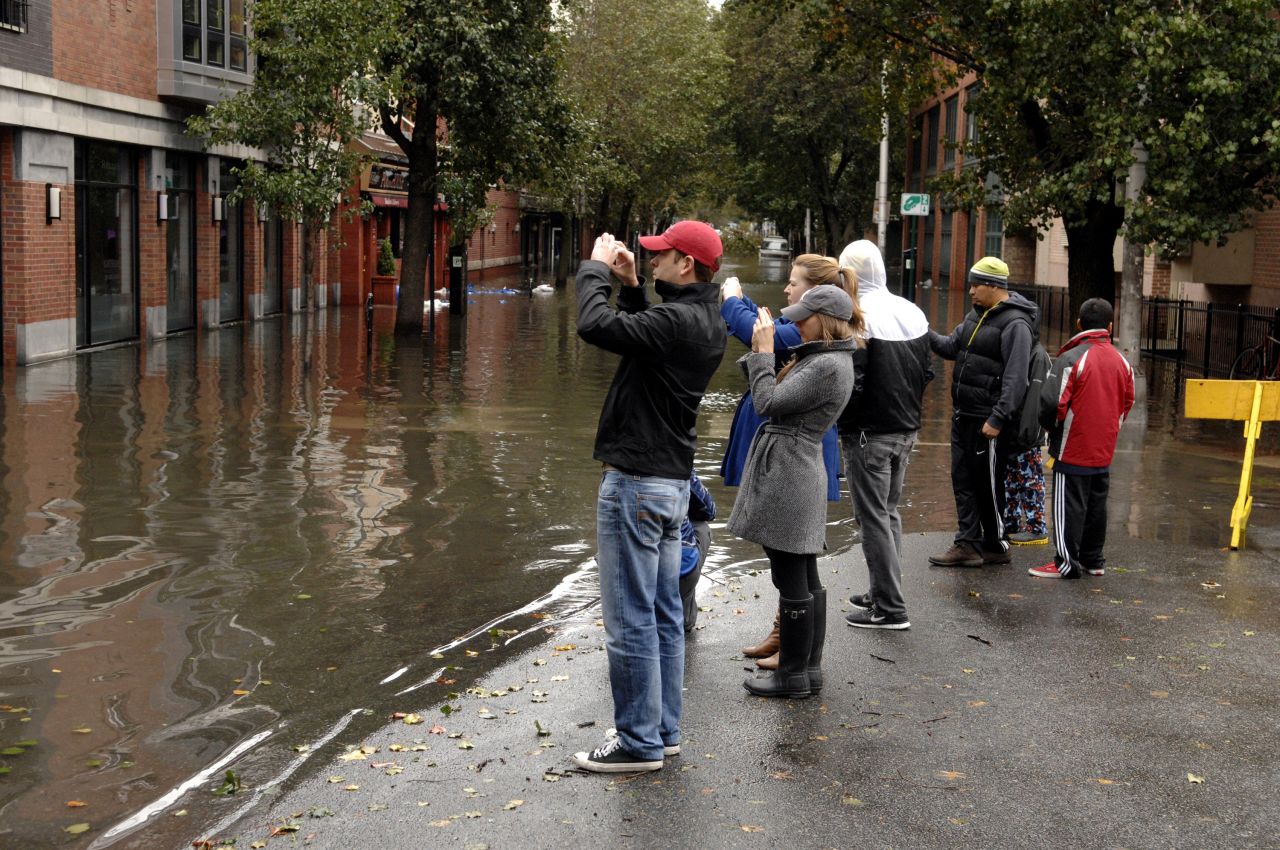 People take pictures of a flooded street Tuesday in Hoboken.