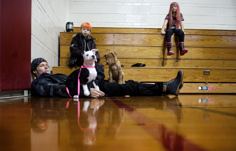 Dover, Delaware, evacuee Thomas Kraidy (left) plays with his puppies Kelo and King  as relatives Deztin Lankford and Cherokee Lankford look on. They found shelter at pet-friendly Milford Middle School gymnasium in Milford, Delaware.
