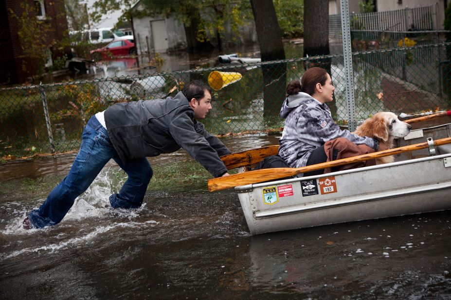 A man pushes a woman and a dog in a boat after their Little Ferry, New Jersey, neighborhood was flooded by Hurricane Sandy.