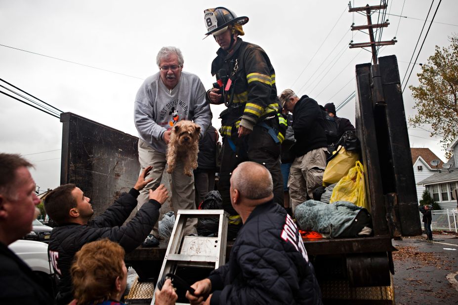 A man being evacuated in New York City hands a dog to first responders in flood waters caused by Hurricane Sandy on October 30, 2012.