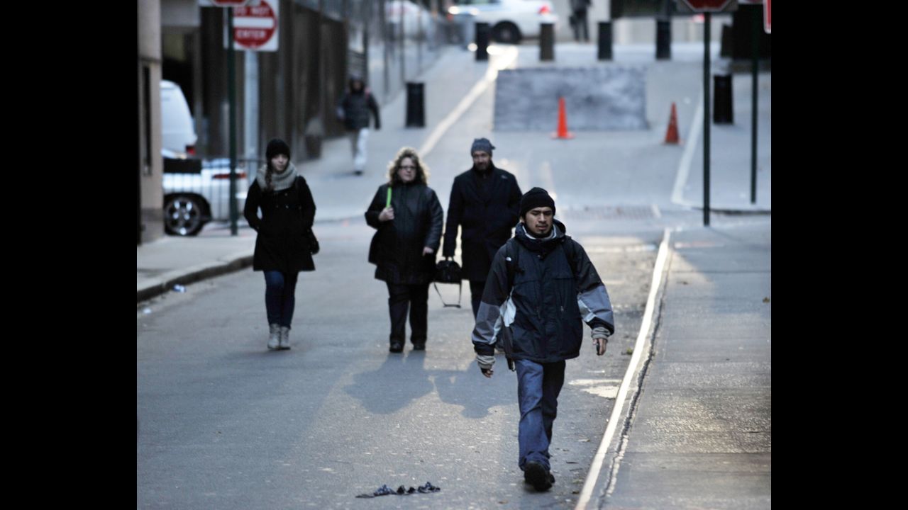 People walk to work Wednesday on a normally busy street near the New York Stock Exchange.