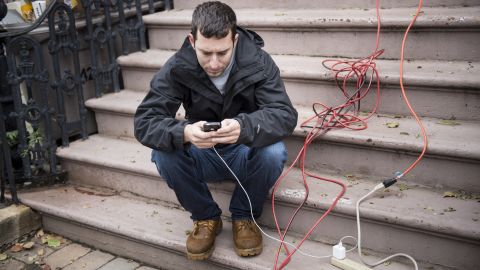 A man charges his cellphone from an extension cord from a home Wednesday that still had power in Hoboken, New Jersey.