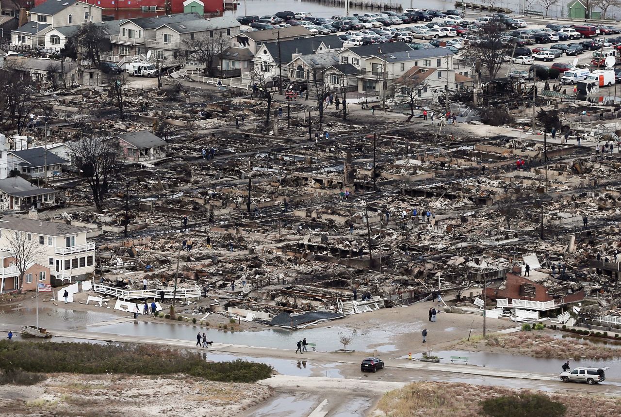 People walk near the remains of burned homes in the Breezy Point neighborhood of Queens, New York, on Wednesday.