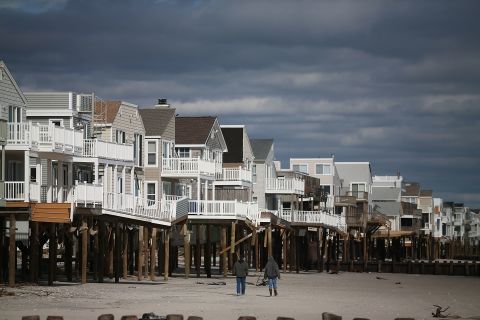 People walk past homes damaged by Hurricane Sandy  in Long Beach Island, New Jersey.