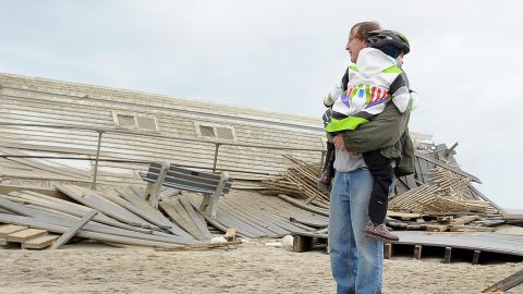 A man carries his daughter as they view Sandy's damage to a New Jersey boardwalk and beach area. 