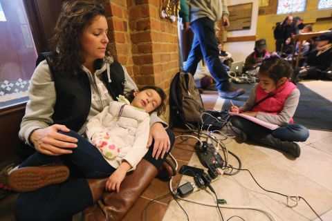 Bridget De La Torre holds her daughter Neve, 3, as daughter Paz sits nearby while they rest and charge devices on Thursday. They were at a shelter for those affected by Superstorm Sandy at Saints Peter and Paul Church in Hoboken, New Jersey. Bridget's family has no electricity or hot water, and their car was destroyed by flooding. 