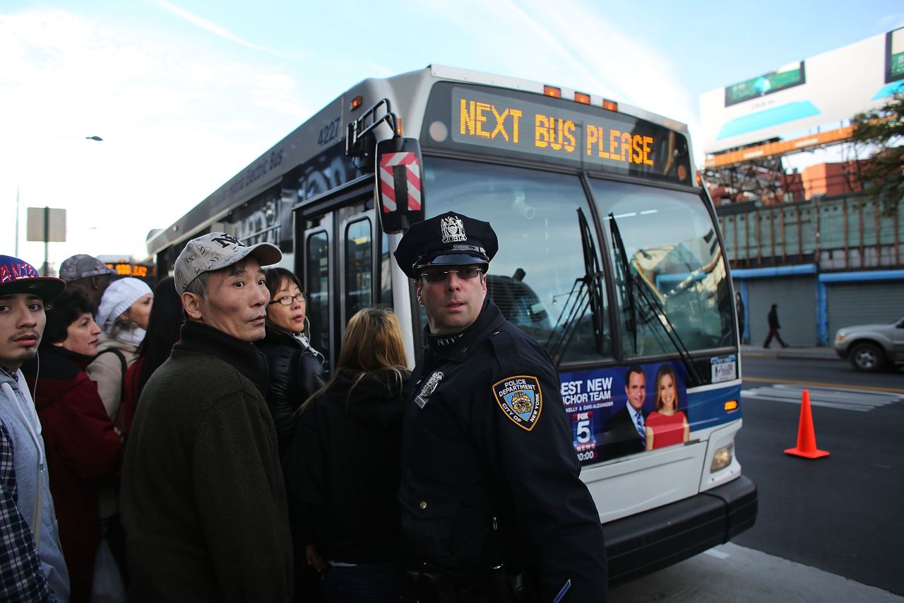 A police officer directs passengers waiting on Thursday to board city buses into Manhattan at the Barclays Center in Brooklyn. About 4,000 buses are replacing the subway lines still closed by Superstorm Sandy damage.