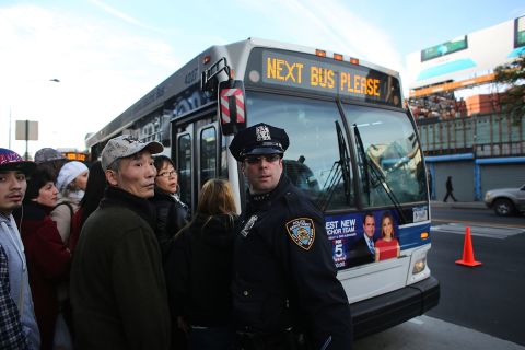 A police officer directs passengers waiting on Thursday to board city buses into Manhattan at the Barclays Center in Brooklyn. About 4,000 buses are replacing the subway lines still closed by Superstorm Sandy damage.