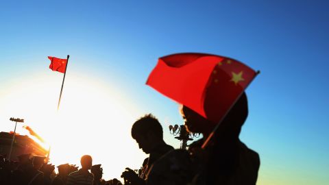 Tourists wait for the lowering of the flag at Tiananmen Square on September 29 in Beijing, China.
