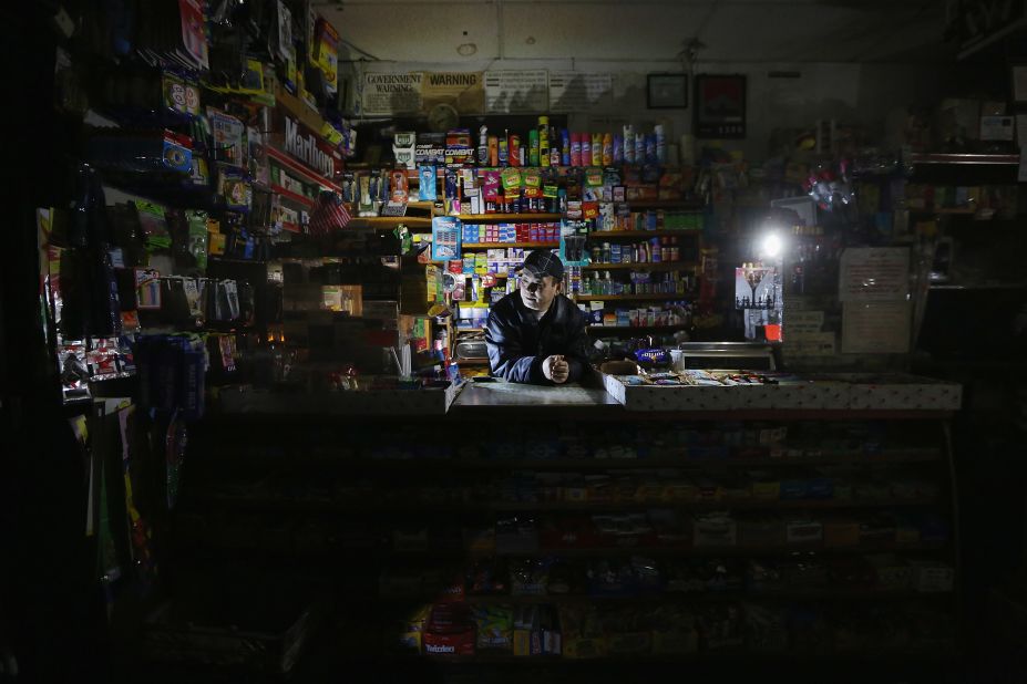Park Choul works by flashlight in his deli in New York's East Village on Thursday, November 1. More than 3.3 million customers remained without electricity in 15 states and the District of Columbia four days after Sandy barreled ashore.