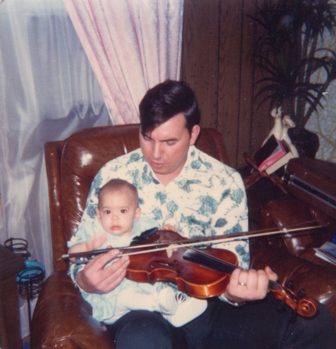 A baby Christal sits on Delmer's lap. He found solace in his music and would sometimes play the guitar eight hours a day.