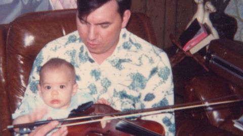 A baby Christal sits on Delmer's lap. He found solace in his music and would sometimes play the guitar eight hours a day.