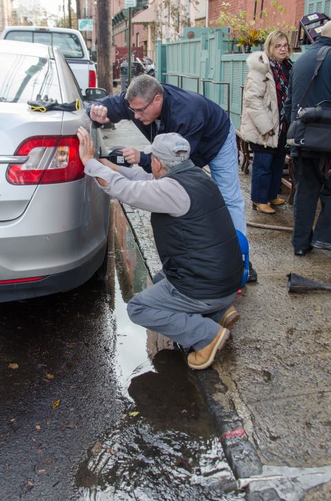 Residents try to siphon gasoline out of their flooded car to use in a generator on Thursday in Hoboken. Power had still not been restored to most of the city three days after Sandy's storm surge flooded the area.
