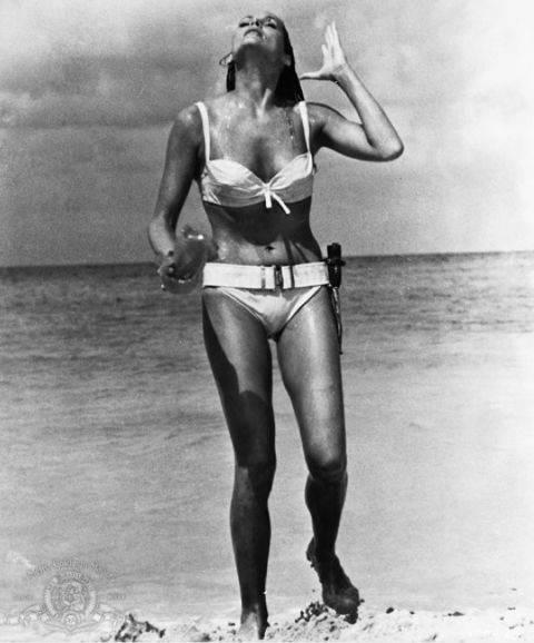 Ursula Andress played Honey Ryder opposite Sean Connery's James Bond in the 1962 film "Dr. No." Bond first sees Ryder as she emerges from the ocean wearing a white bikini. She asks him, "What are you doing here? Looking for shells?" He replies, "No. I'm just looking."