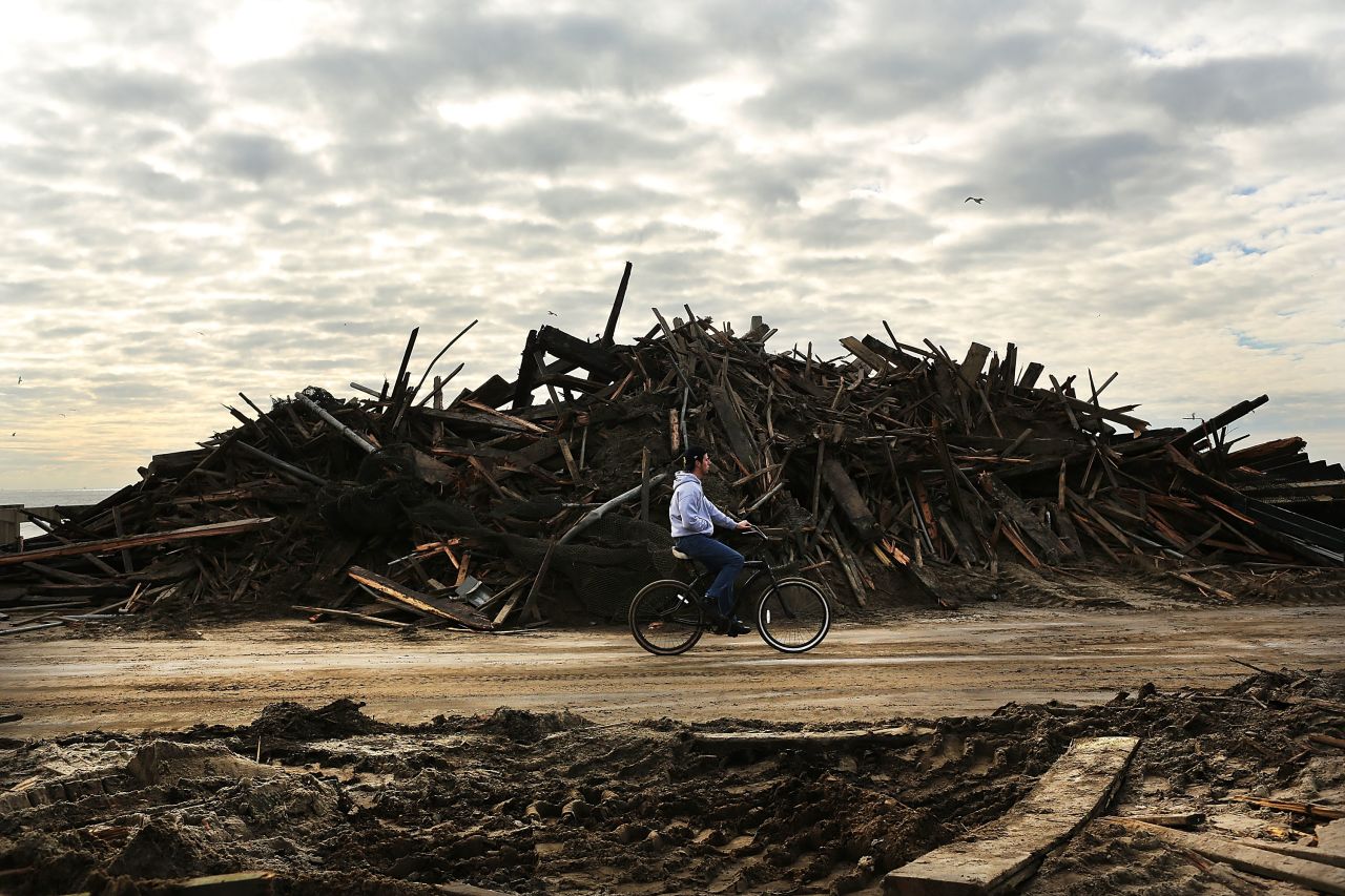 A man rides his bike through the heavily damaged Rockaway neighborhood.