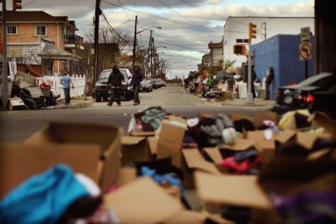 People gather among debris from Superstorm Sandy and boxes of donated goods on Saturday in Rockaway Beach.