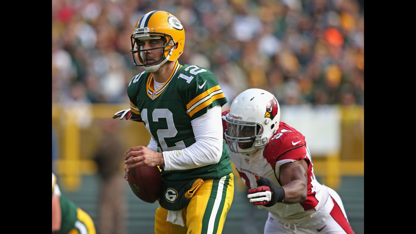 Aaron Rodgers of the Packers escapes from Sam Acho of the Cardinals on Sunday.