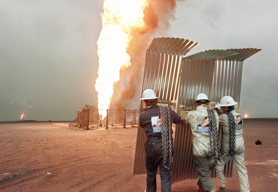 Specialist firefighters approach a burning well in a Kuwaiti oil field as they prepare an attempt to cap it in March 1991.