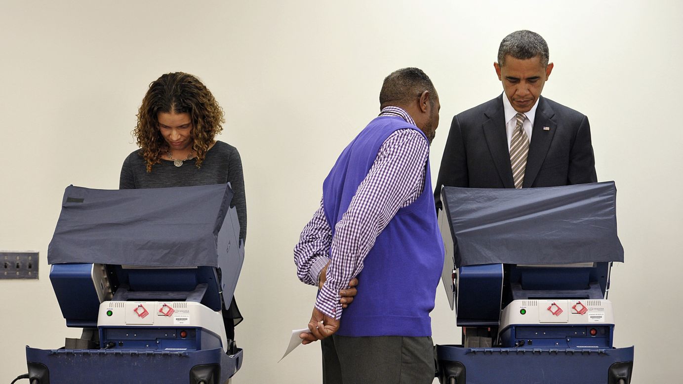 An election worker helps President Barack Obama as he votes early at the Martin Luther King Community Center in Chicago on October 25.