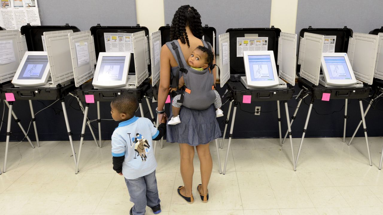 Jaime Grant carries her 11-month-old daughter, Brynn, and holds her 3-year-old son Brian's hand as she casts her ballot during early voting in College Park, Georgia, on October 19.