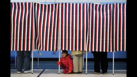 A young girl peered out from under a voting booth as her mother cast a ballot at the Bishop Leo O'Neil Youth Center in Manchester, New Hampshire. 