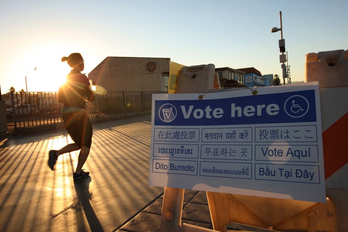 A jogger on The Strand in the Los Angeles area community of Hermosa Beach passes a directional sign to a polling place at sunrise Tuesday.