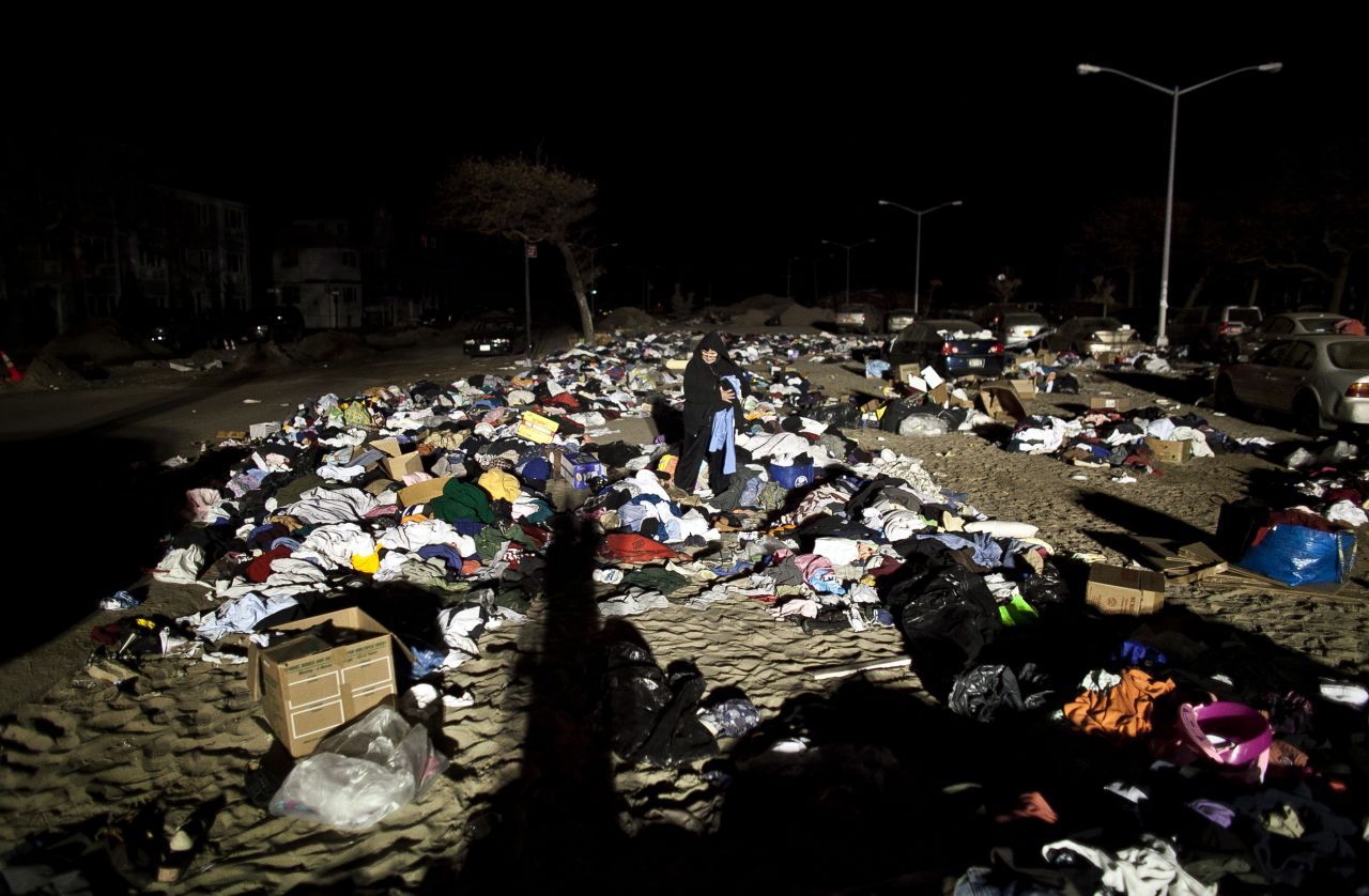 A woman looks through a sand covered parking lot used as a donation center on November 5 in the Rockaway neighborhood of the Queens borough of New York City.