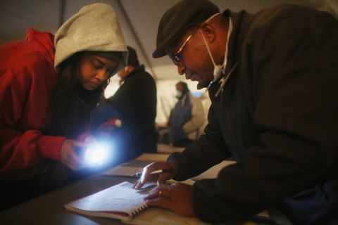 Voter Sheresa Walker used a flashlight for poll worker Lloyd Edwards in a tent set up as a polling place in Queens, New York. The area is still reeling from Superstorm Sandy. 