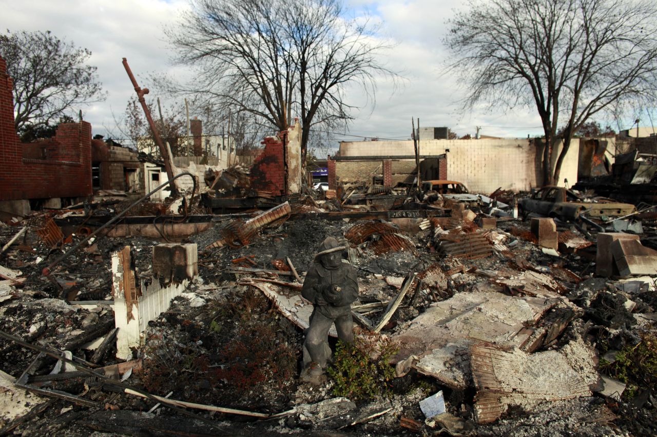 A statue of a firefighter stands in front of a burned down house Sunday in Rockaway, New York.