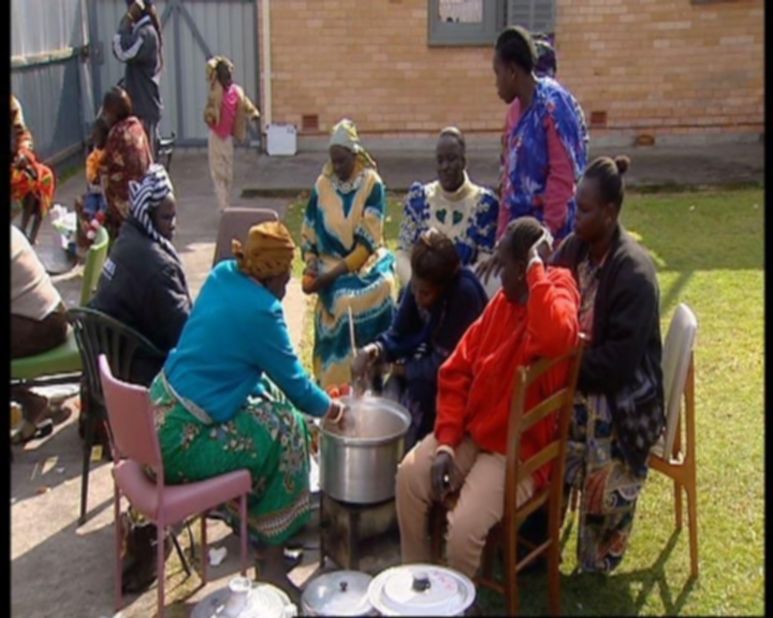 Cooking is women's work in the Dinka culture of South Sudan. These women are cooking in the backyard of a house in Adelaide, Australia.