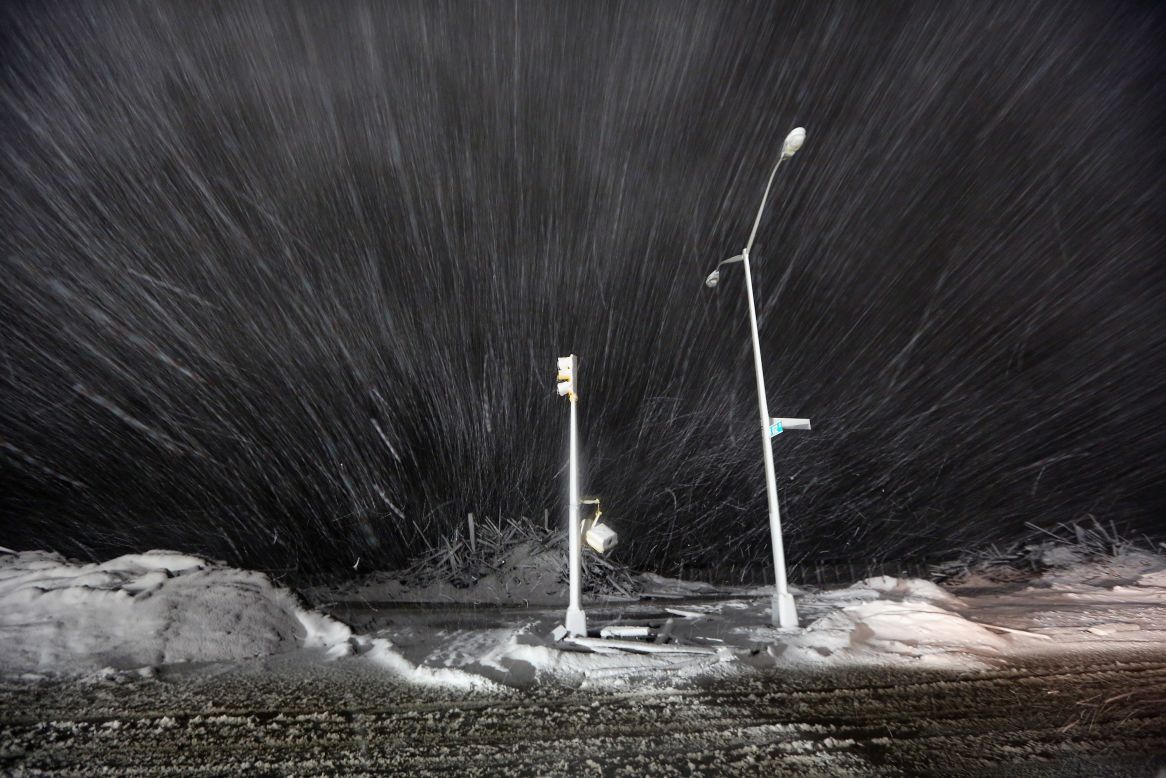 Snow blows past debris and nonfunctioning streetlights on Wednesday in Rockaway.